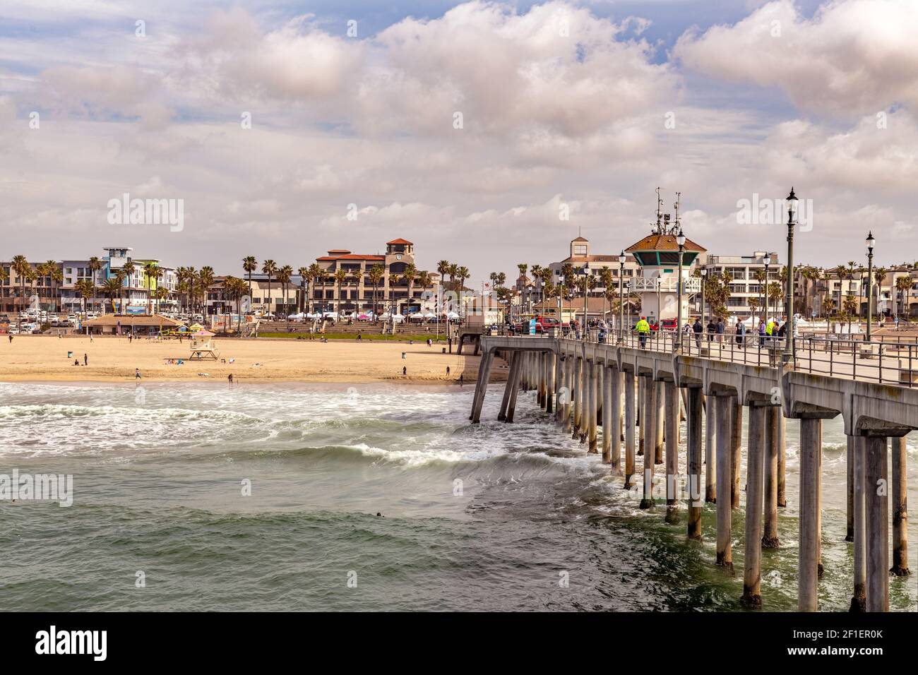 Huntington Beach pier and shoreline show why this area is a popular tourist attraction, with its vibrant skies and bustling commerce. Stock Photo