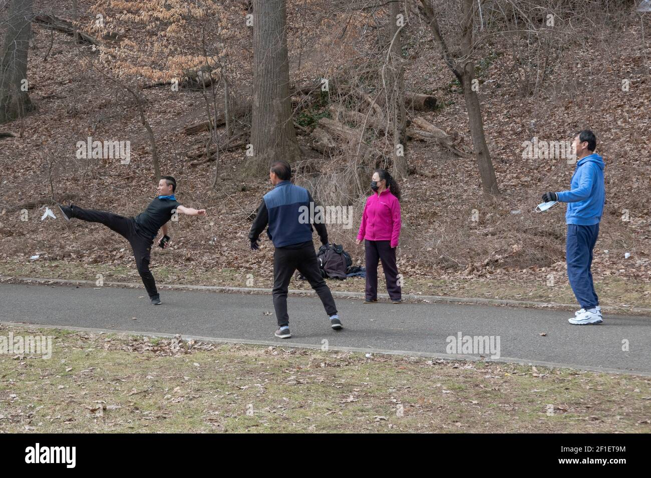 $ Chinese Americans - 3 men & a woman - play jianzi in a park in Queens, New York City. Stock Photo