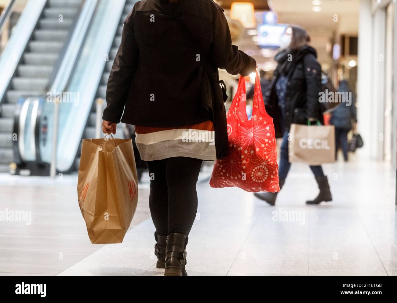 Norderstedt, Germany. 08th Mar, 2021. Customers wait in line for admission  in front of a store at the Herold-Center in Norderstedt. In contrast to the  neighboring city of Hamburg, customers here can