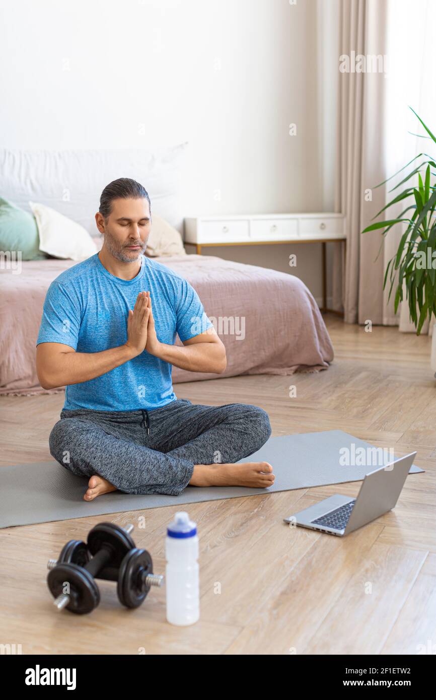 Man during online steaming. Meditation practice - prayer pose. Vertical photo. Stock Photo