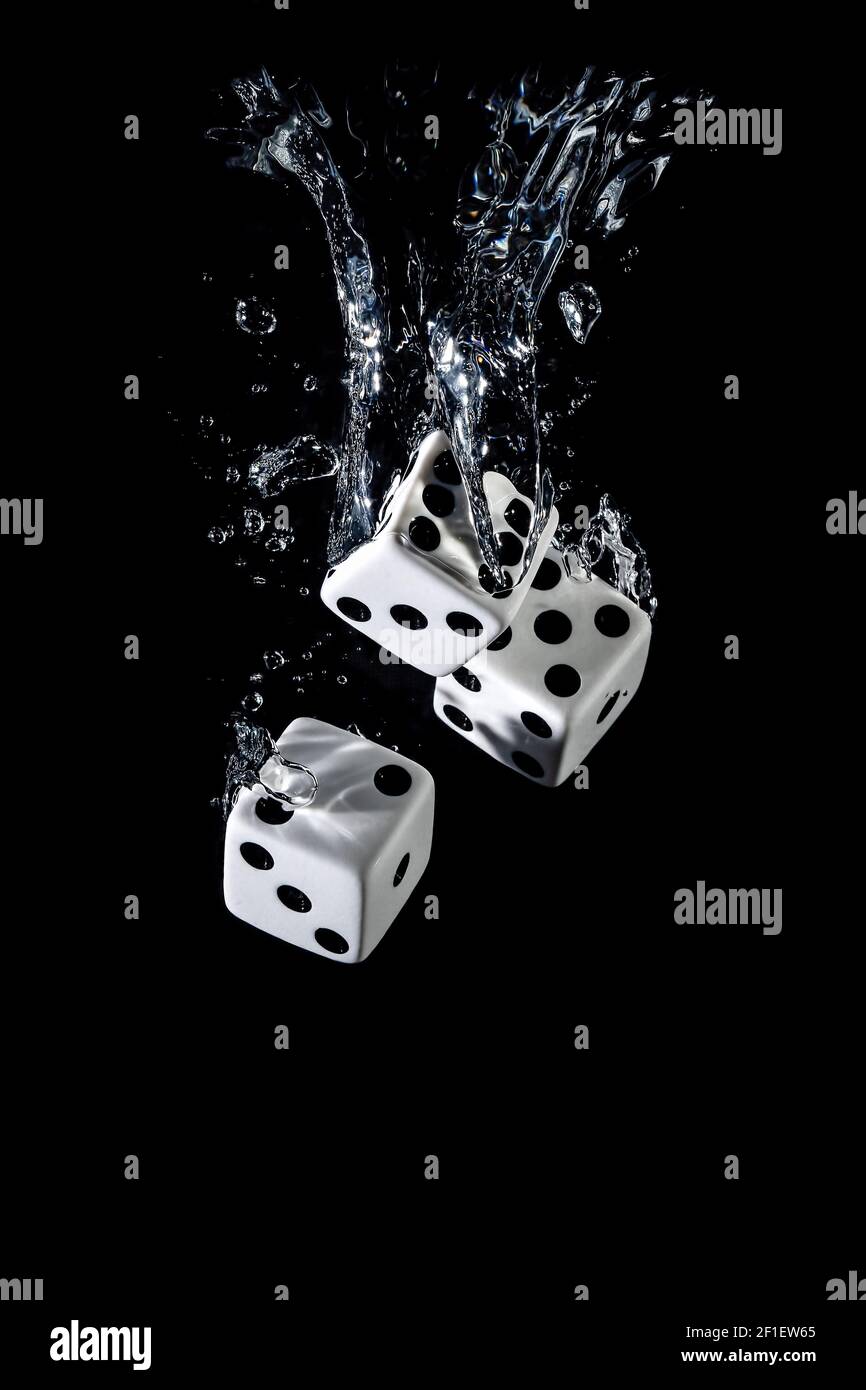 Dices sinking in water with bubbles on black background Stock Photo