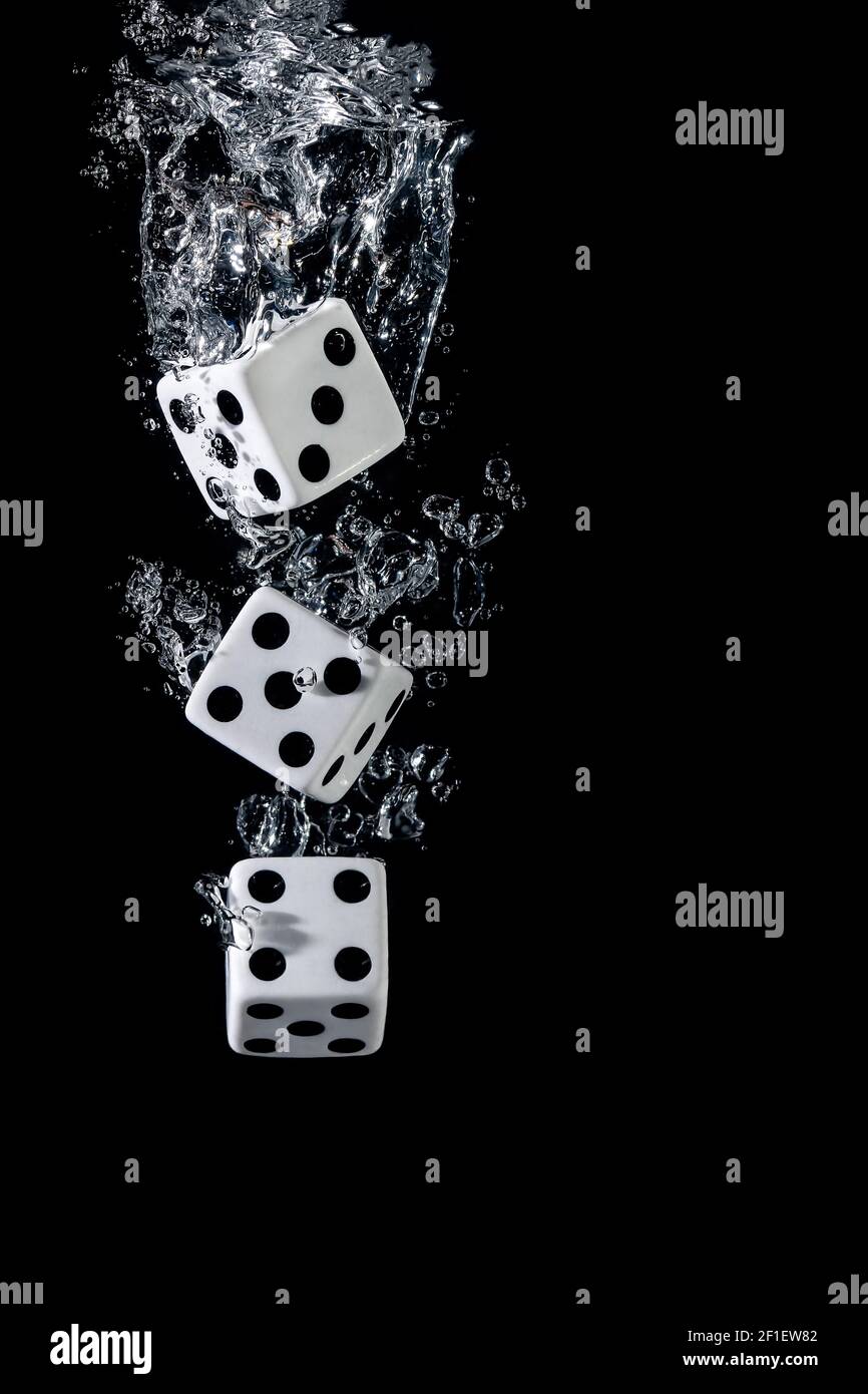 Dices sinking in water with bubbles on black background Stock Photo