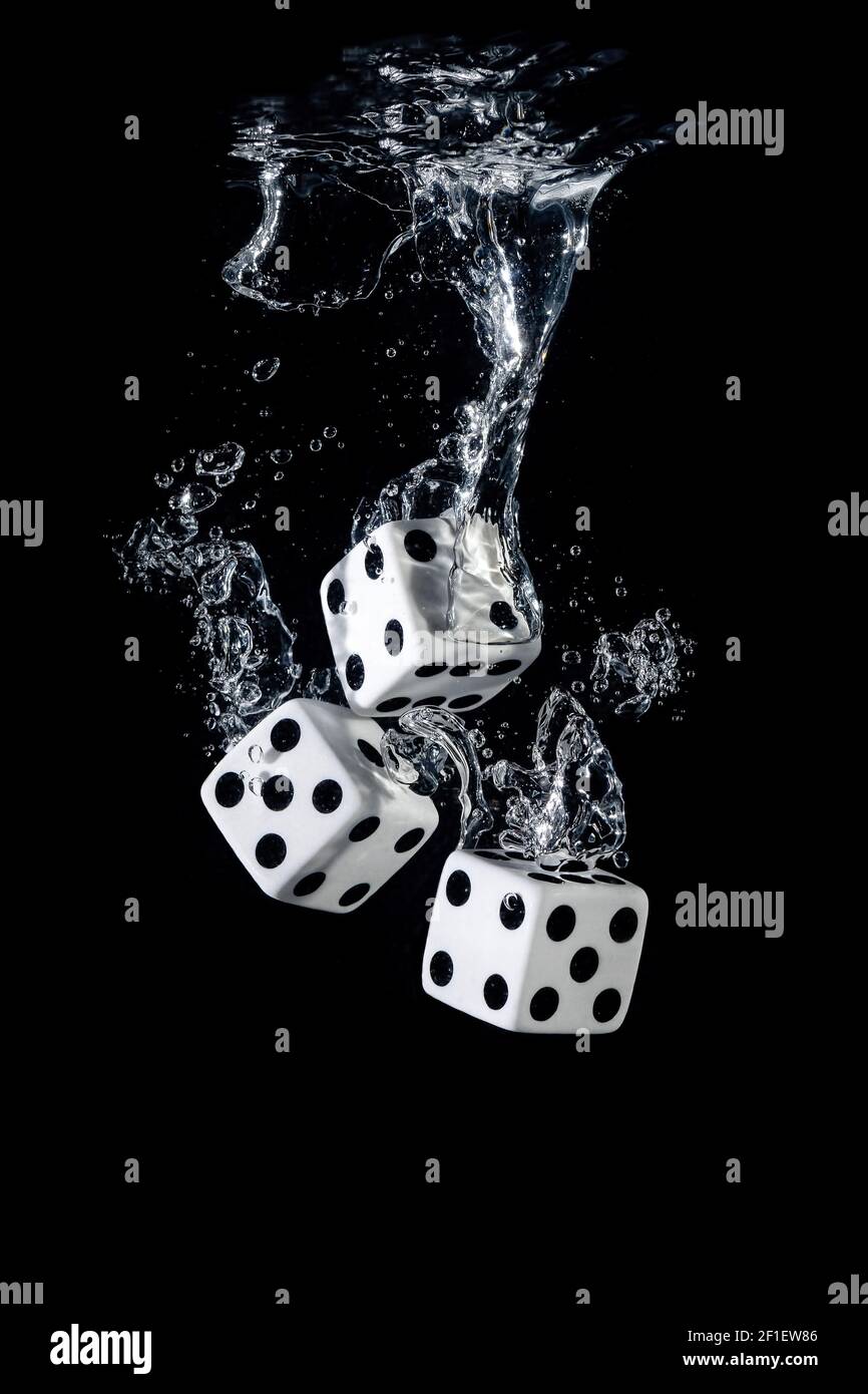 Dices sinking in water with bubbles on black background Stock Photo