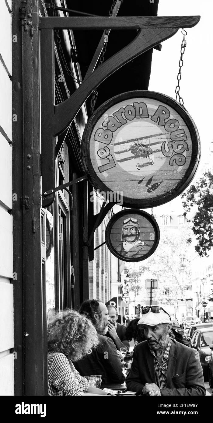 PARIS, FRANCE - SEPTEMBER 1, 2018:  Tourists and locals have a drink at outdoor terrace  of famous Le Baron Rouge wine bar. Black white historic photo Stock Photo