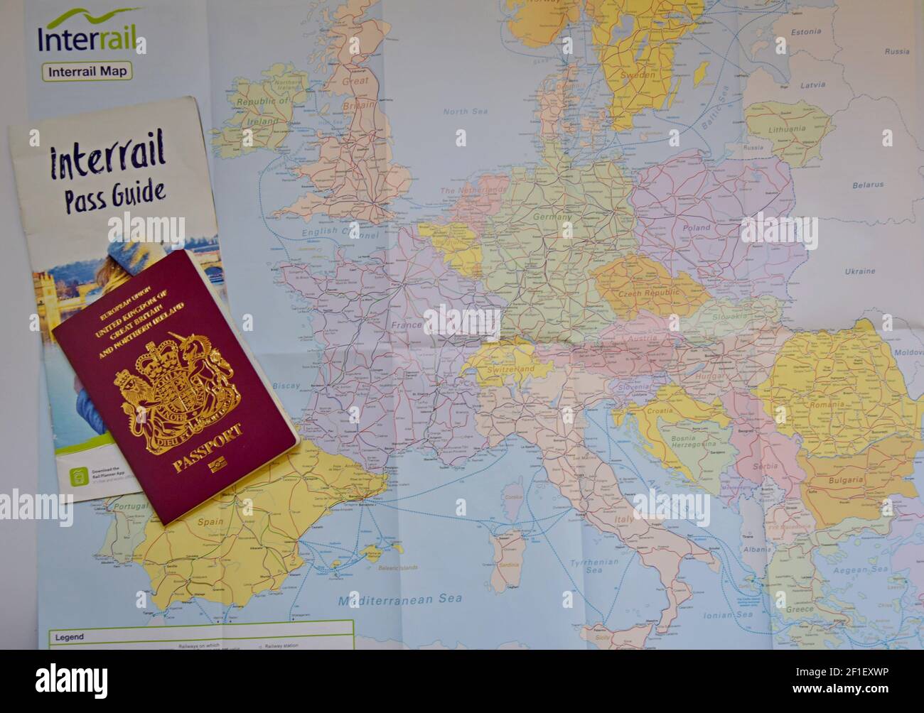 A British Passport with an Interrail guide laying on an Interrail map of Europe, ready to travel by train across Europe Stock Photo