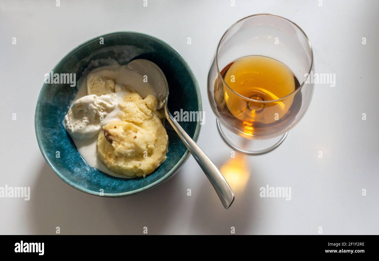 A bowl of bread pudding with vanilla ice cream and a snifter of brandy Stock Photo