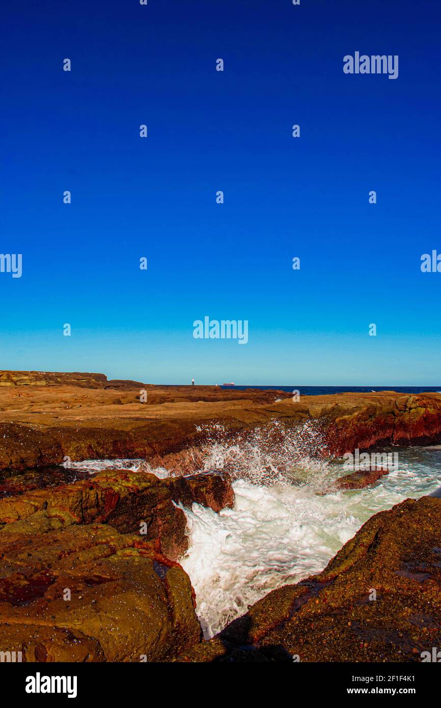 A vertical shot of a rocky seashore near the wavy sea Stock Photo - Alamy