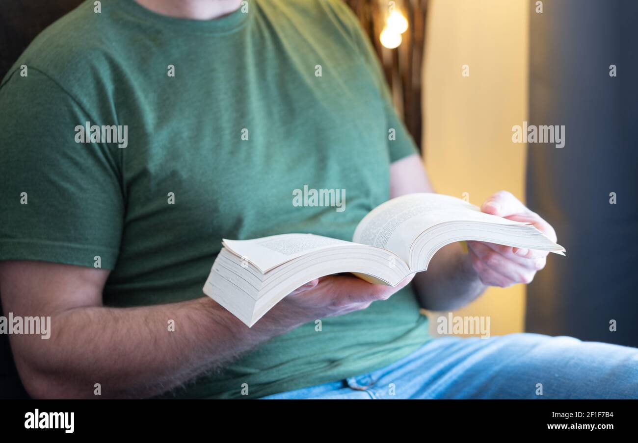 midsection of man wearing casual clothes reading book on sofa Stock Photo