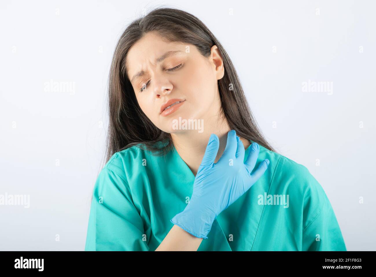 Photo of a young woman doctor in green uniform touching her neck Stock ...