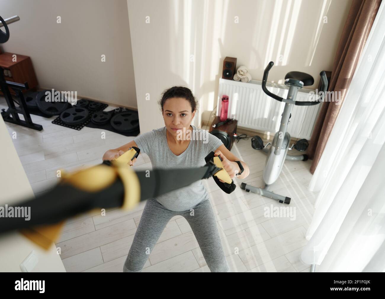 High angle view of athletic woman exercising at home with fitness straps. Home workout concept Stock Photo
