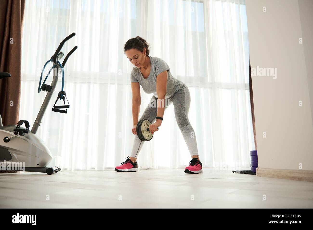 Young woman performing abs exercises with gymnastic roller for flat ...