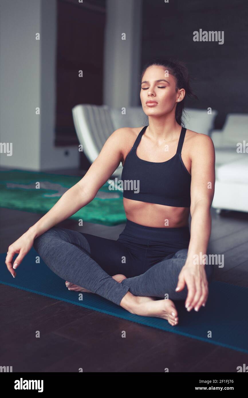 Young Caucasian woman meditating during yoga exercise indoors, eyes closed Stock Photo