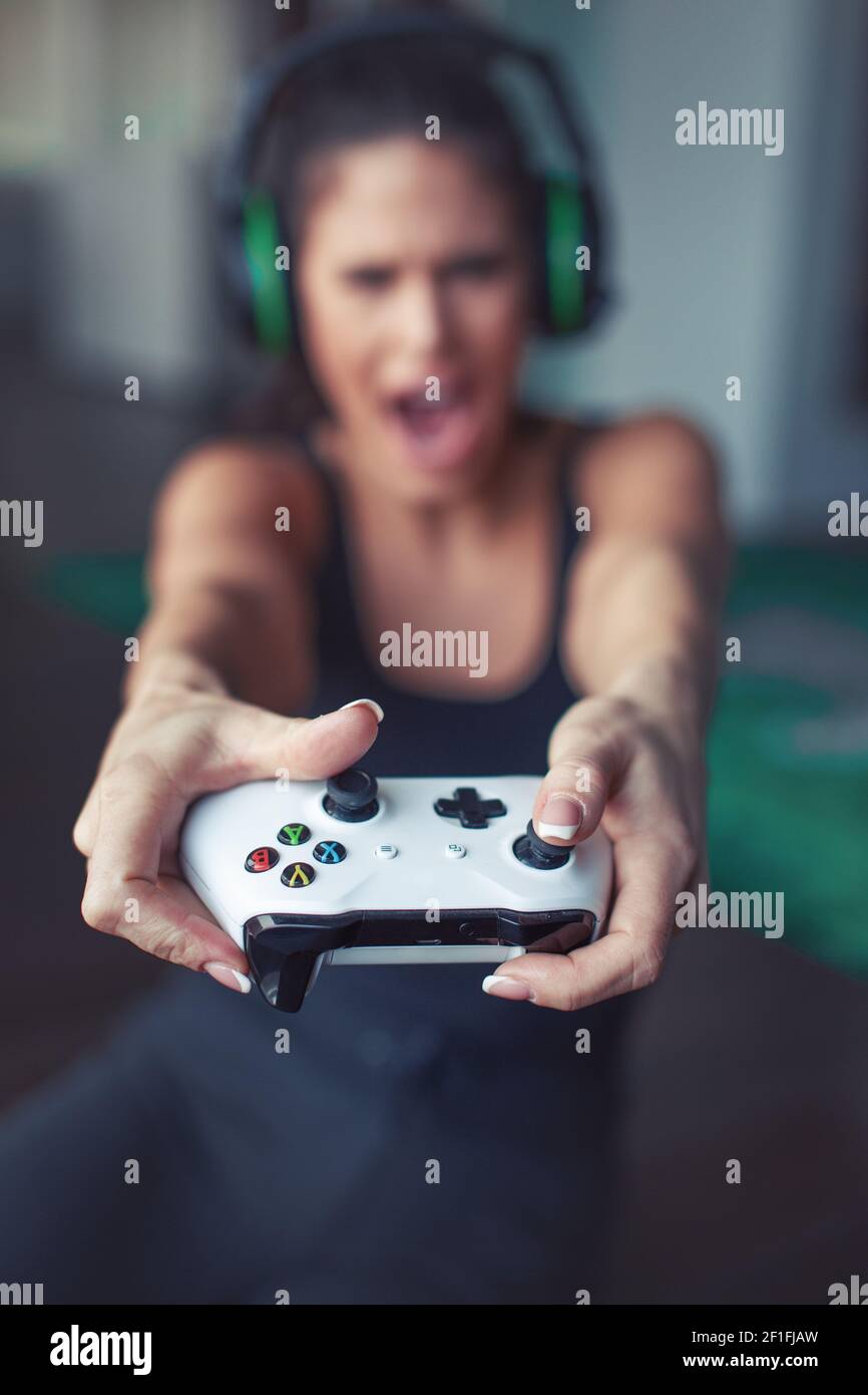 Young Caucasian gamer woman pushing button on console and shouting depth of field Stock Photo