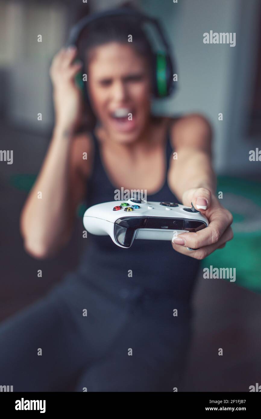 Young Caucasian gamer woman shouting while playing online on console, depth of field Stock Photo