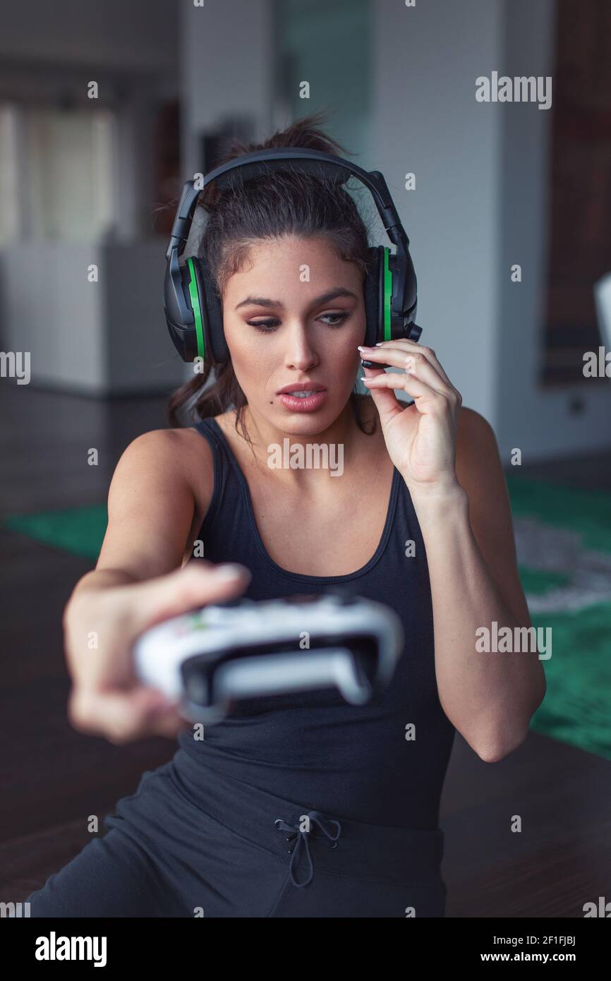 Young Caucasian gamer woman asking question while playing online console game, depth of field Stock Photo