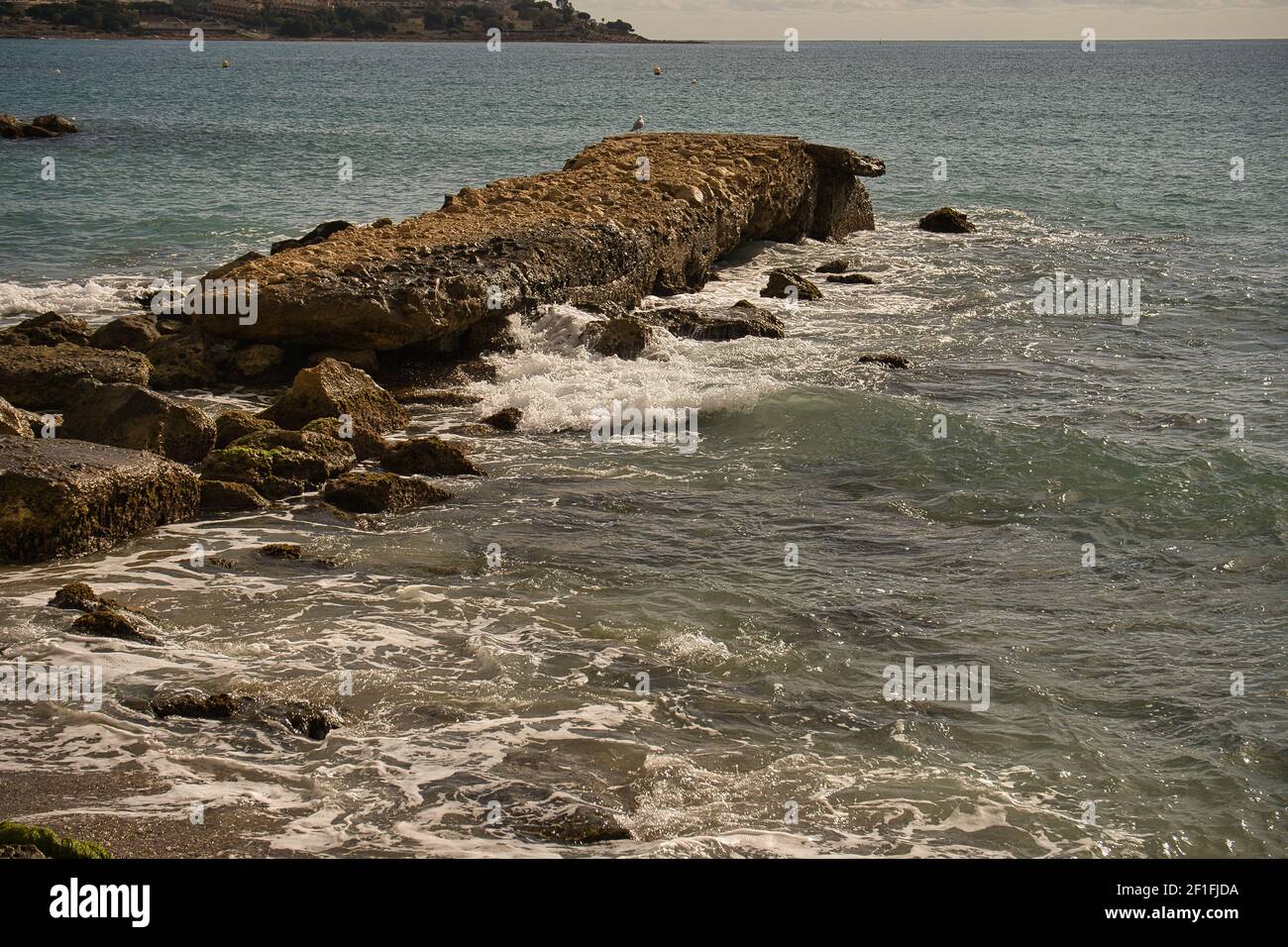 Sea waves lash line impact rock on the beach, located in Alicante, Spain, Stock Photo