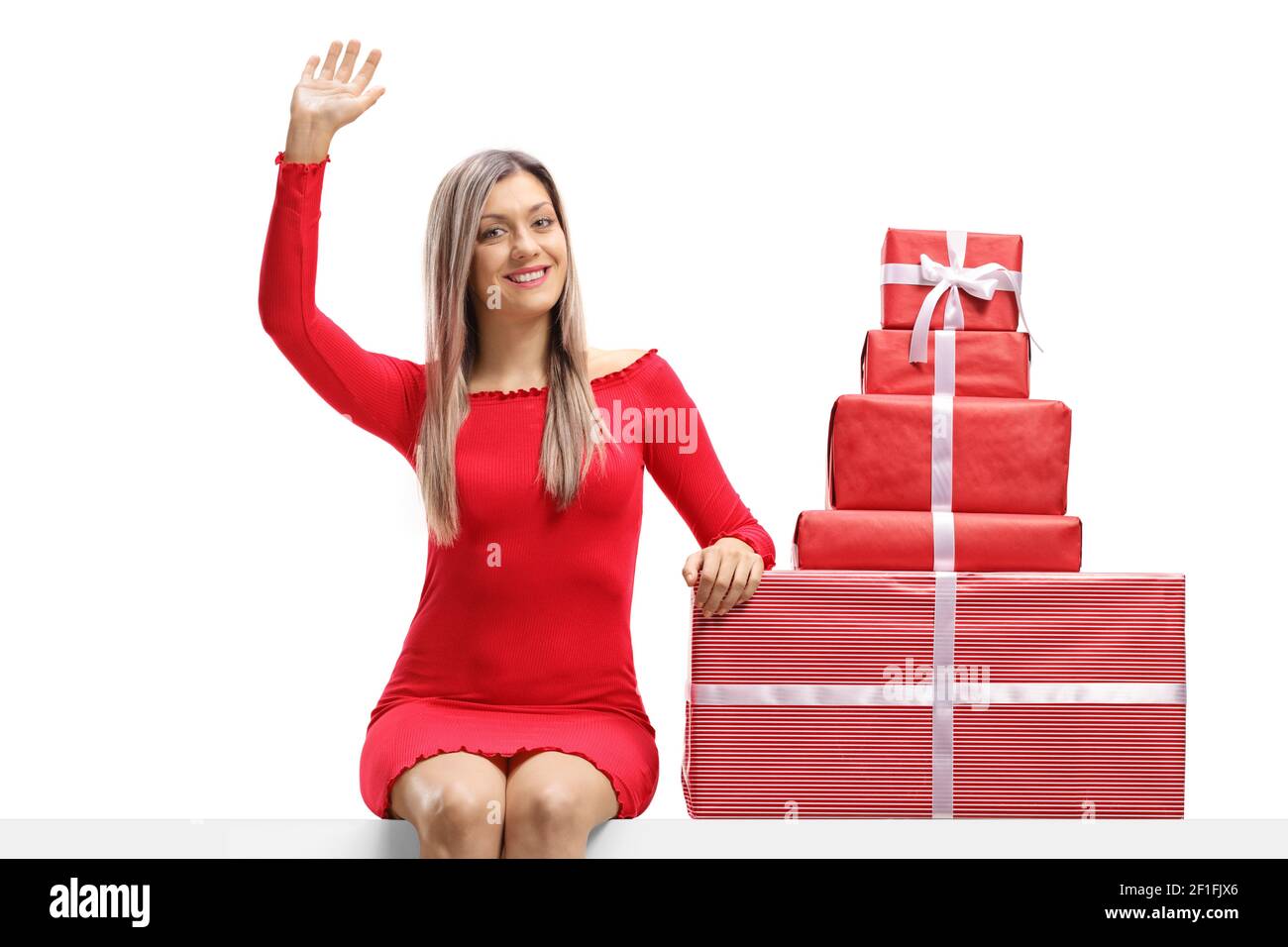 Woman in a red dress sitting on a banner with presents and waving ...