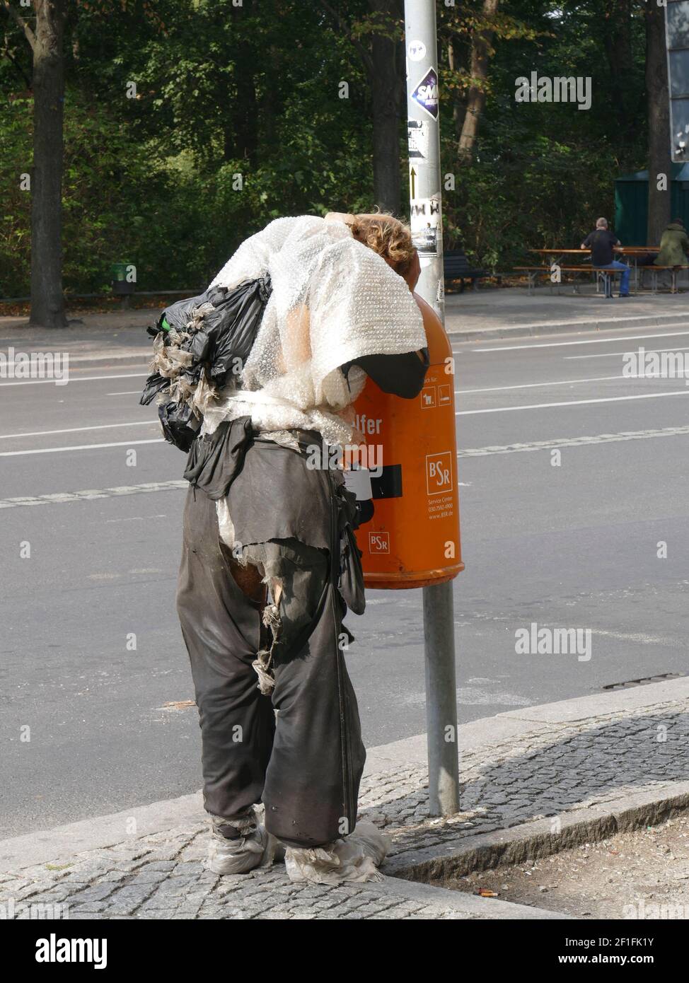 Homeless man looking for food in the garbage Stock Photo