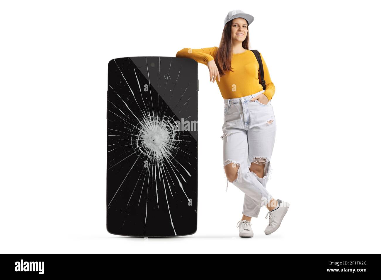 Full length portrait of a teenage girl leaning on a phone with a cracked screen isolated on white background Stock Photo
