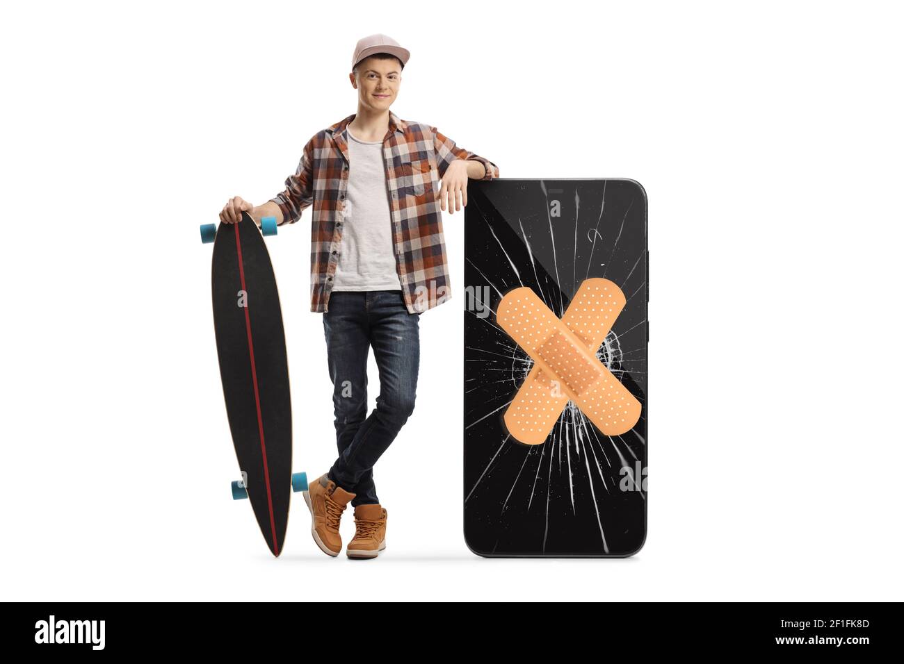 Full length portrait of a skater guy with a longboard posing next to a phone with a cracked screen and bandage isolated on white background Stock Photo