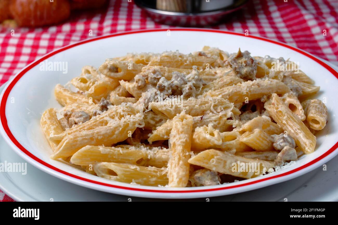 Italian pasta. Plate with penne rigate topped with cream and sausage ...