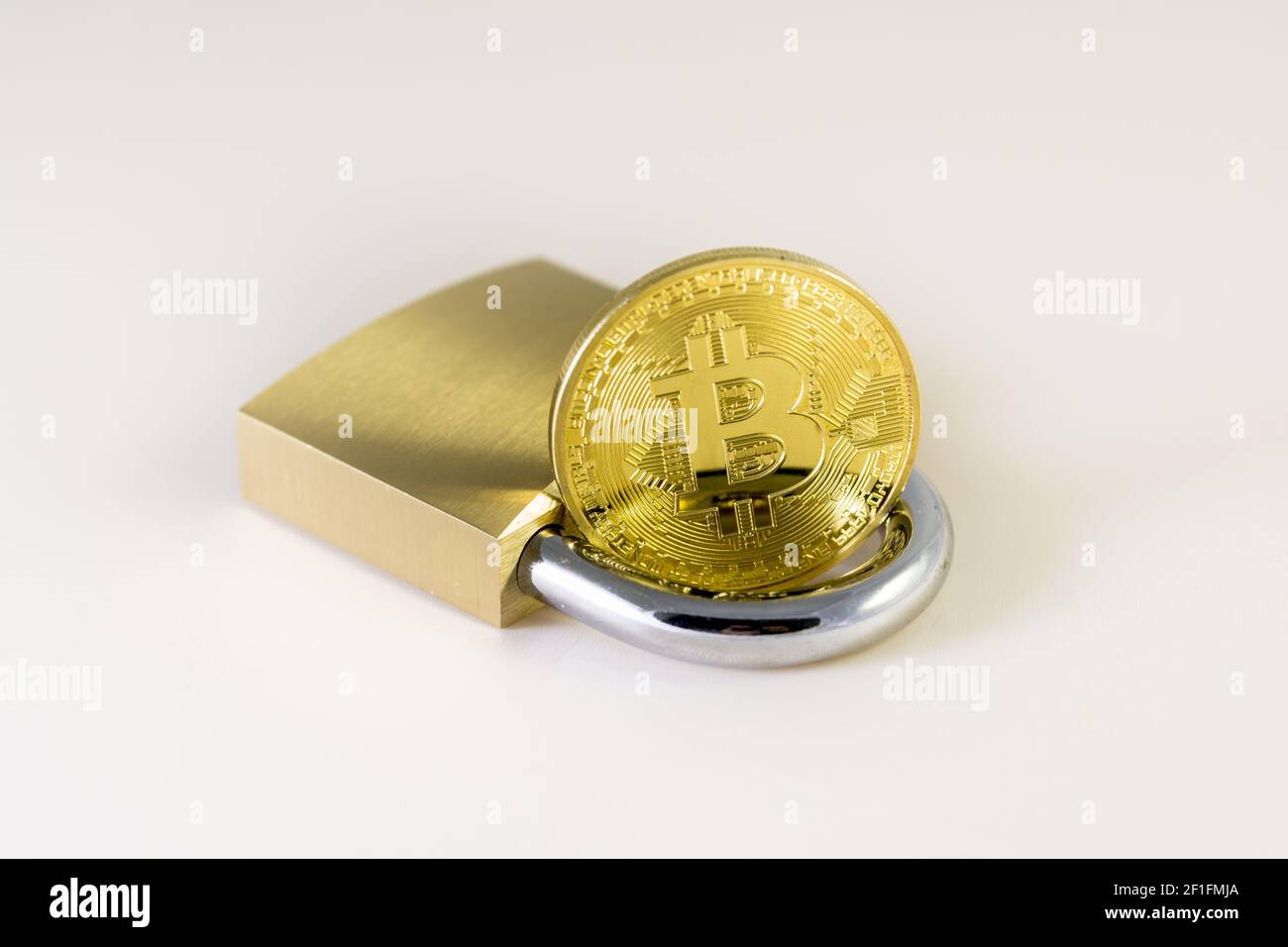 Bitcoin over a padlock isolated on white Stock Photo