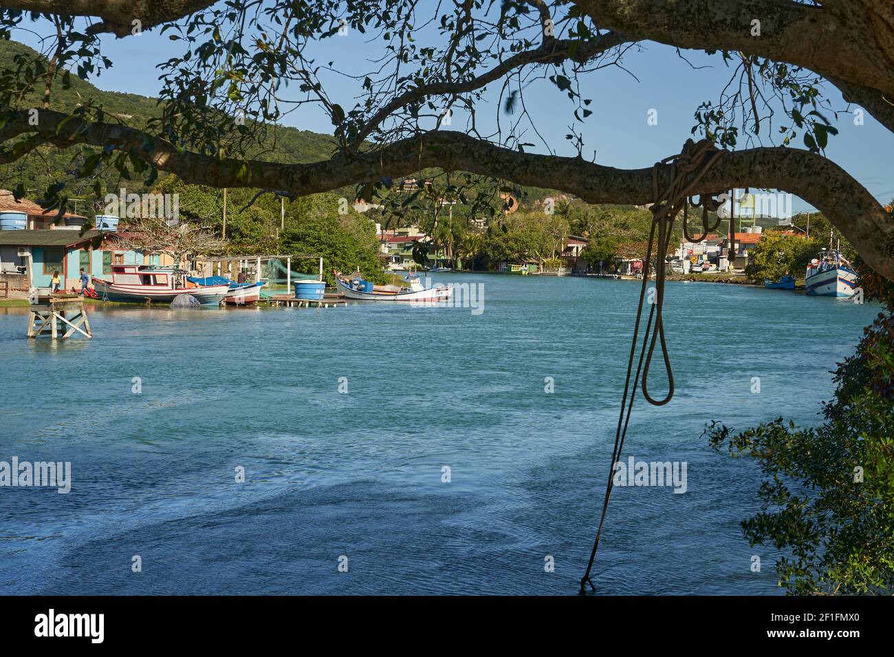 beautiful river landscape with old wooden buildings, wooden boats and a rope hanging from a tree. Tranquil turquoise river meandering through a pretty Stock Photo