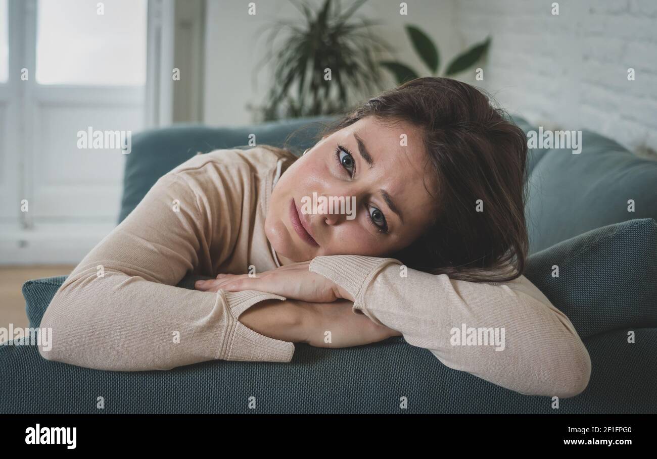 Depressed sad attractive woman crying on sofa couch at home feeling lonely tired and worried suffering depression in mental health, loneliness and iso Stock Photo