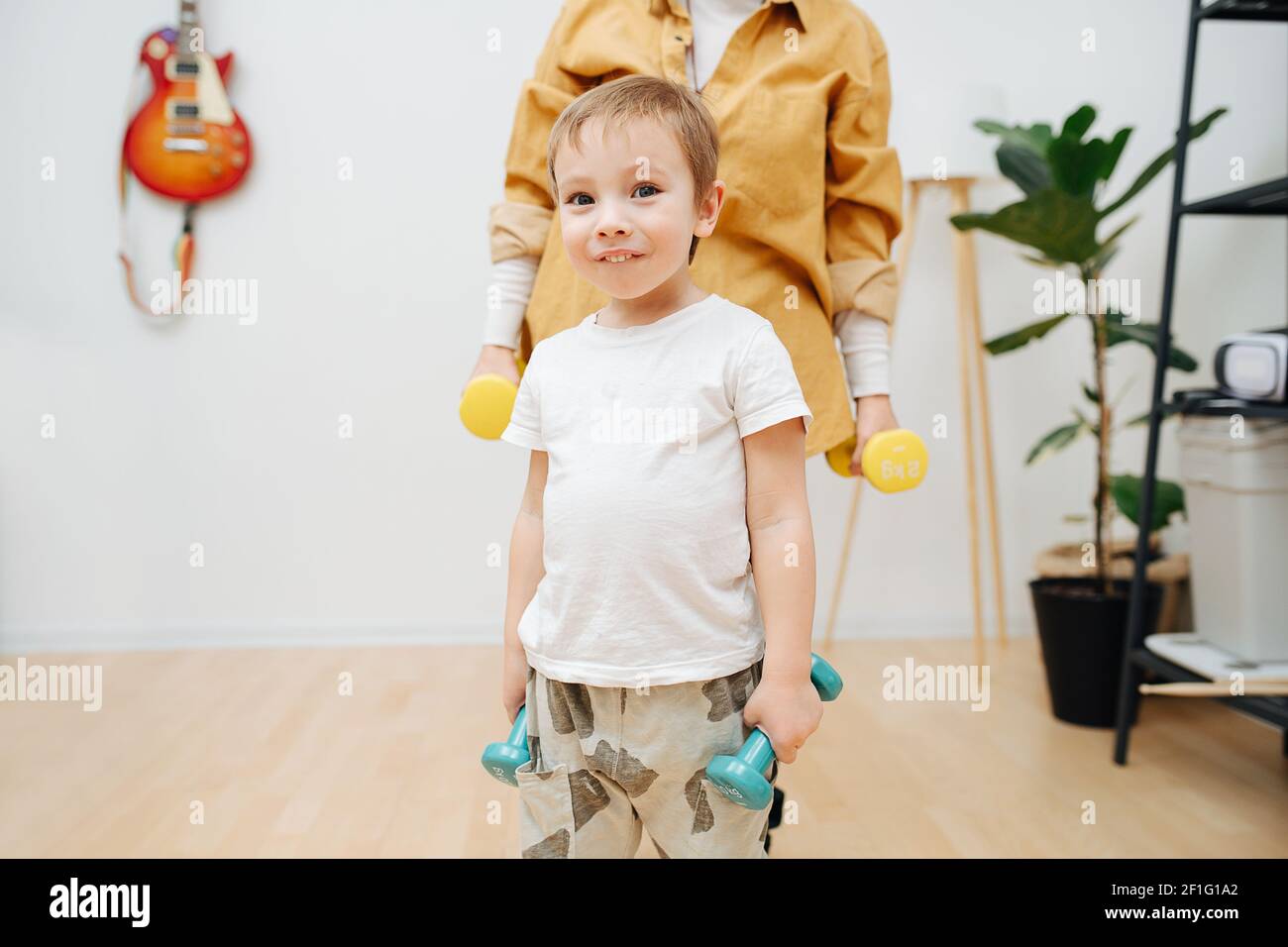 portrait of a toddler with dumbbells in his hands against of his grandmother. High quality photo Stock Photo