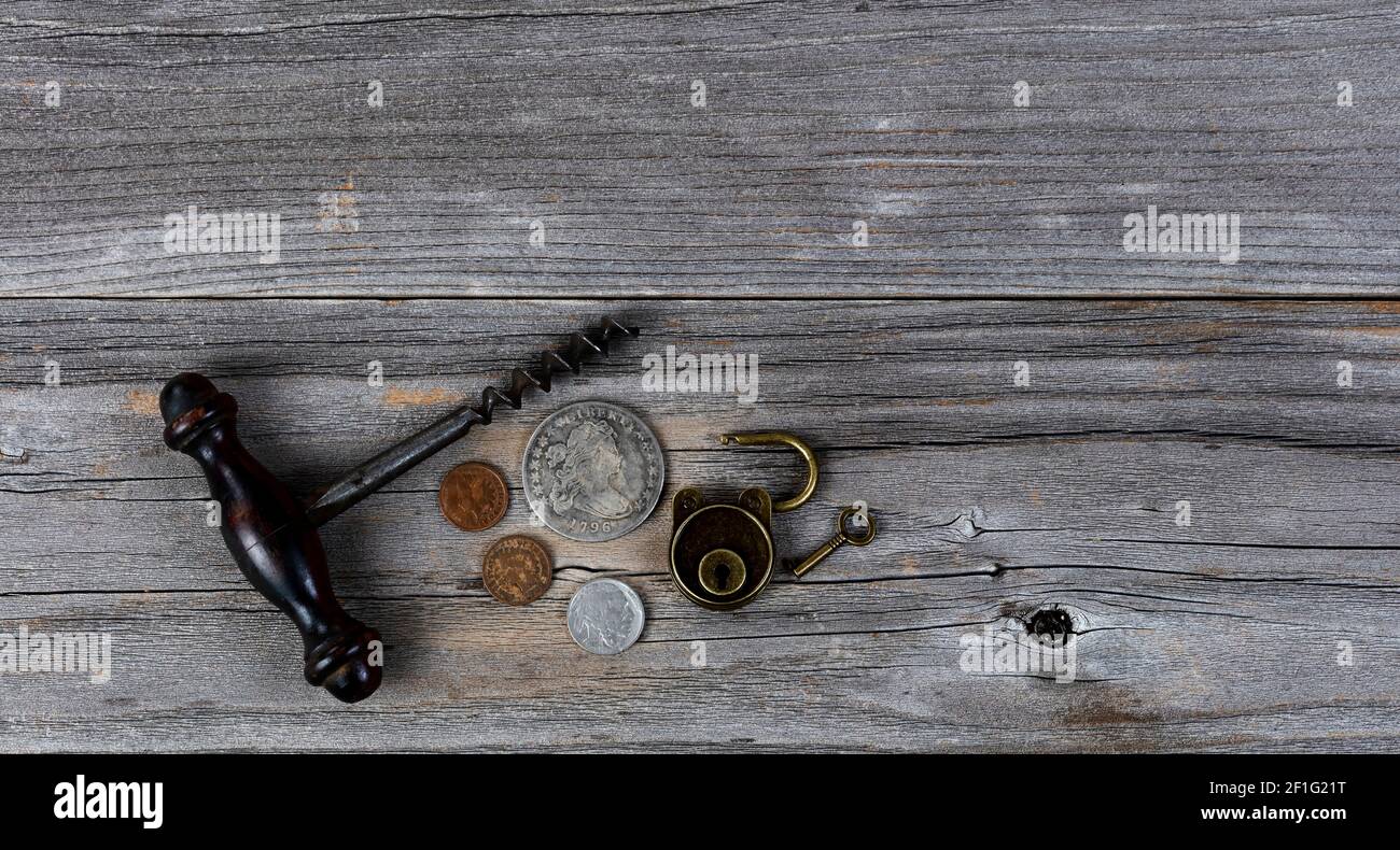 Vintage collection of coins, wine corkscrew and antique lock on weathered wooden planks Stock Photo