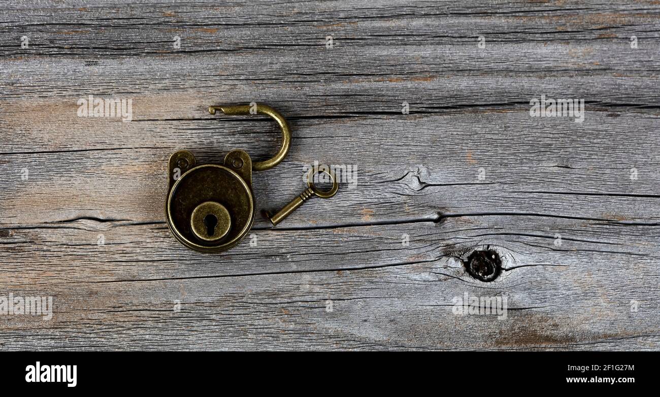 Close up of open antique lock with key on vintage wooden plank
