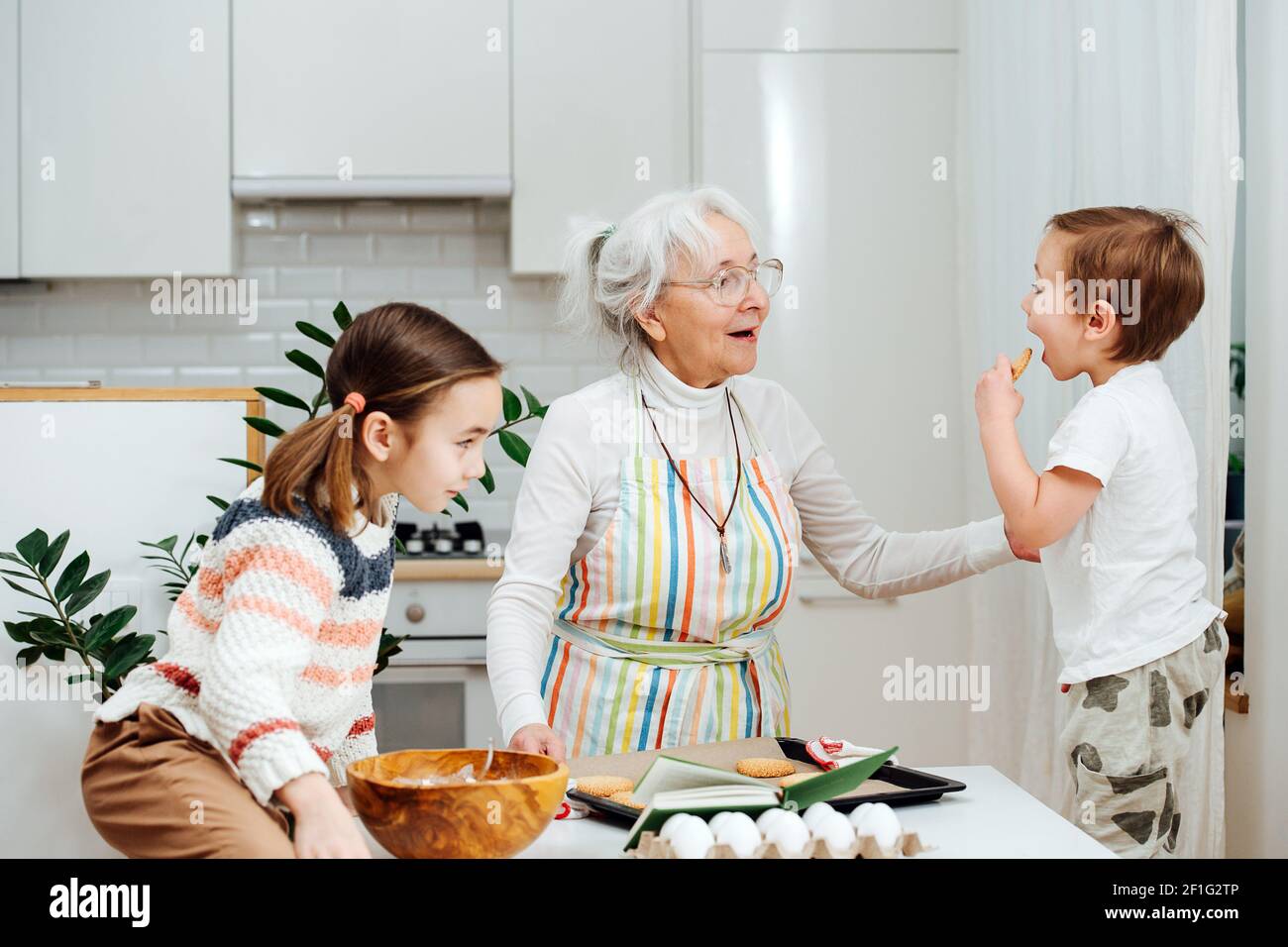 Siblings visiting their grandmother, they make cook together. The boy says he's hungry Stock Photo