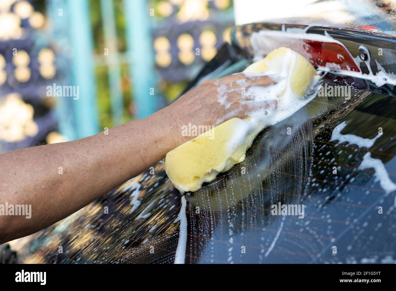 Hand washing car with soapy water. Man cleans car with sponge, water