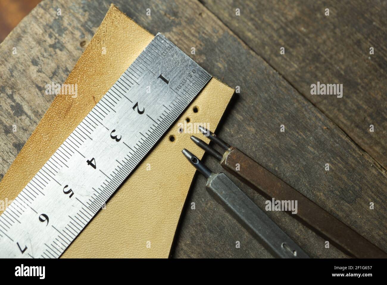 Set of leather 1-hole punchers on piece of leather and liner. Instruments of leather master working process. Stock Photo