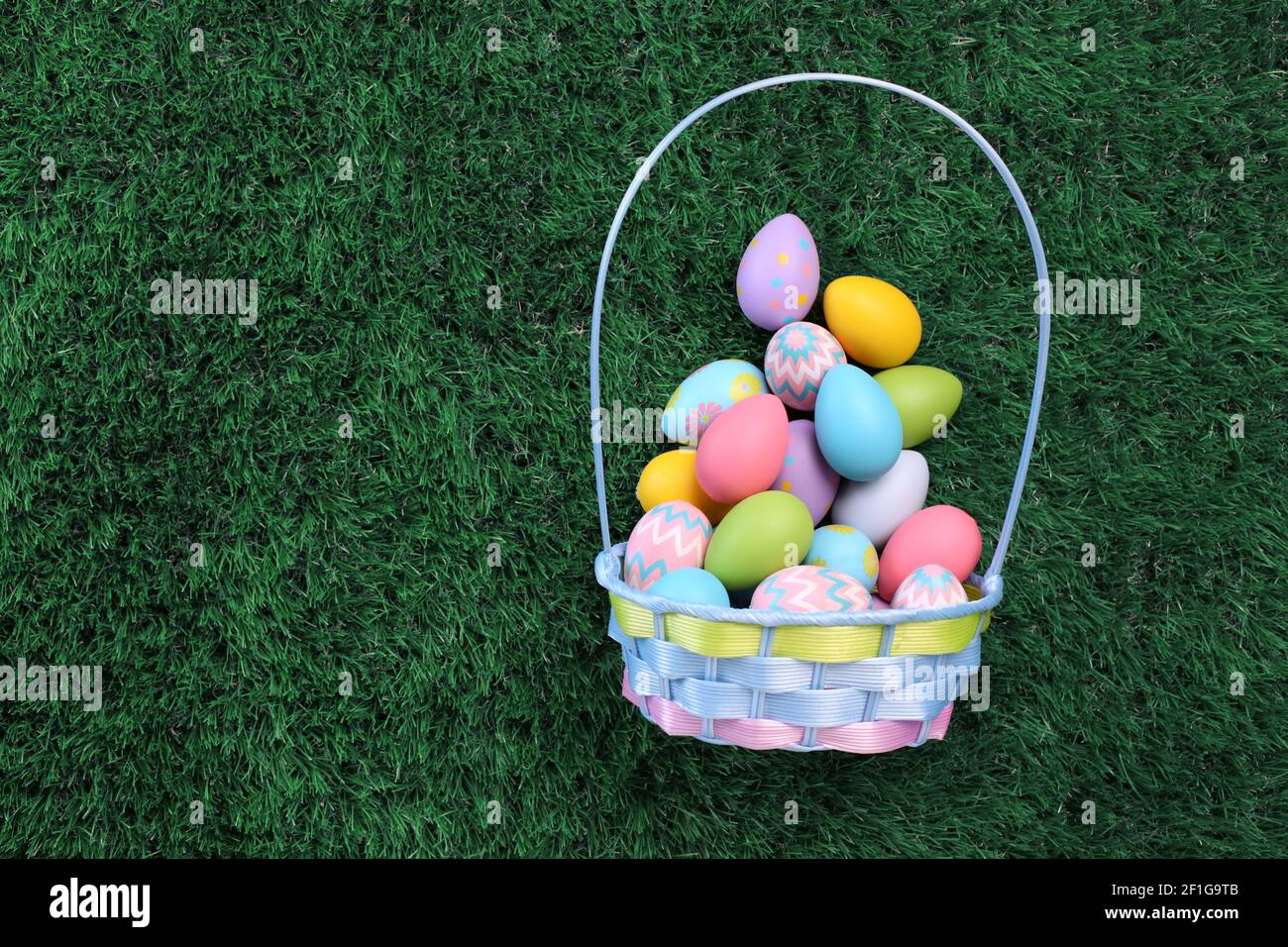 Easter eggs basket filled with colorful Easter eggs on green grass Stock Photo
