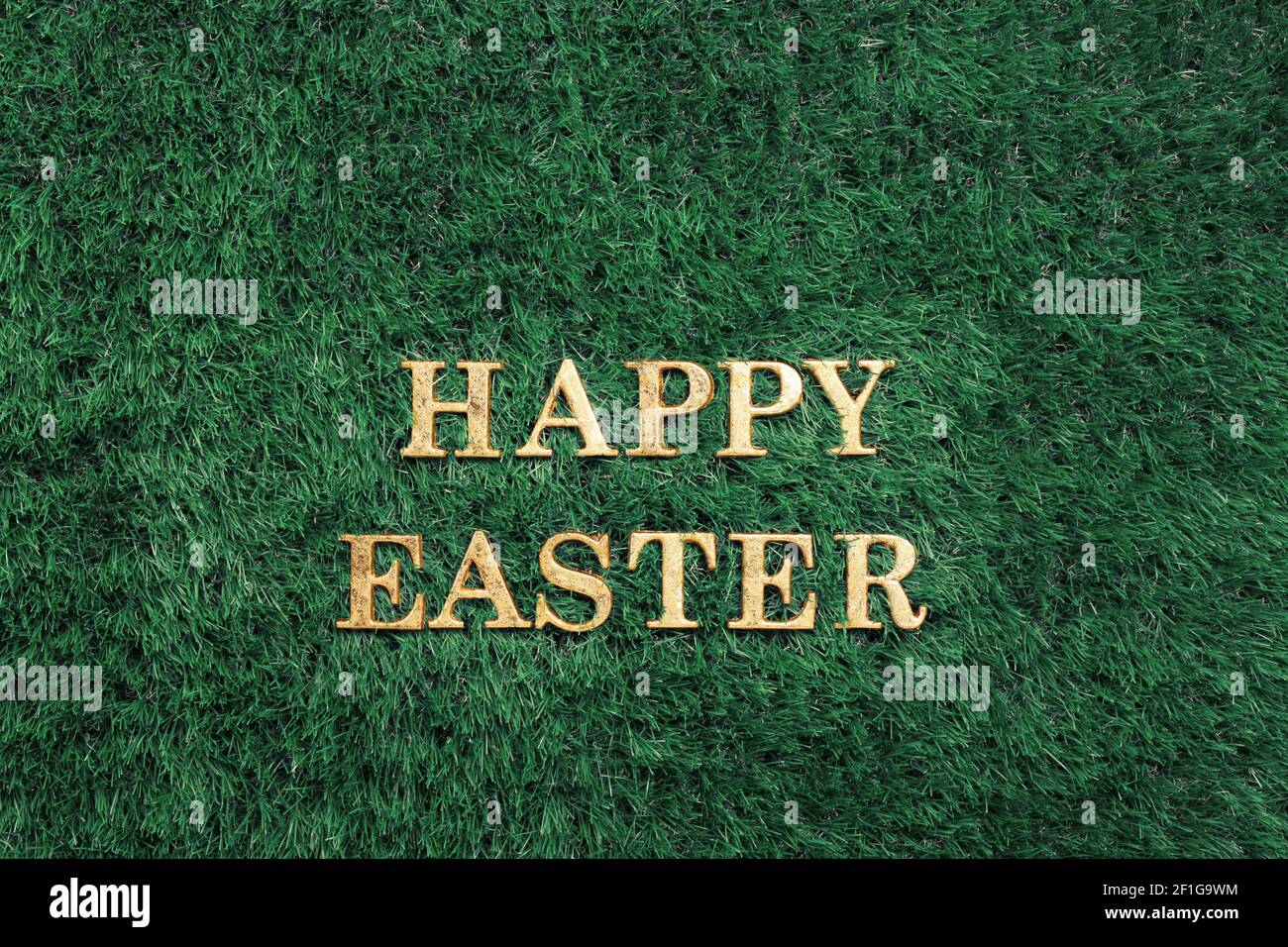 Happy Easter gold text laying in green grass Stock Photo