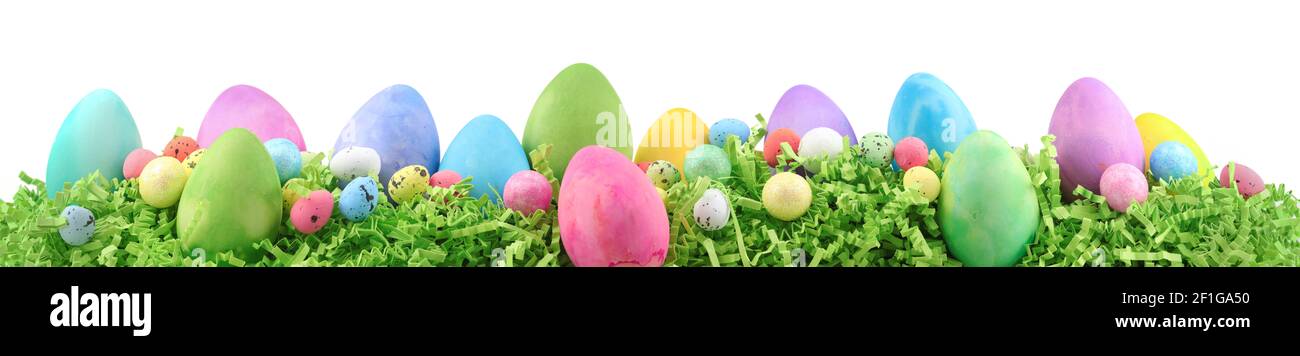 Painted Easter eggs and decorations on arranged on Easter grass. Horizontal banner isolated on white. Stock Photo