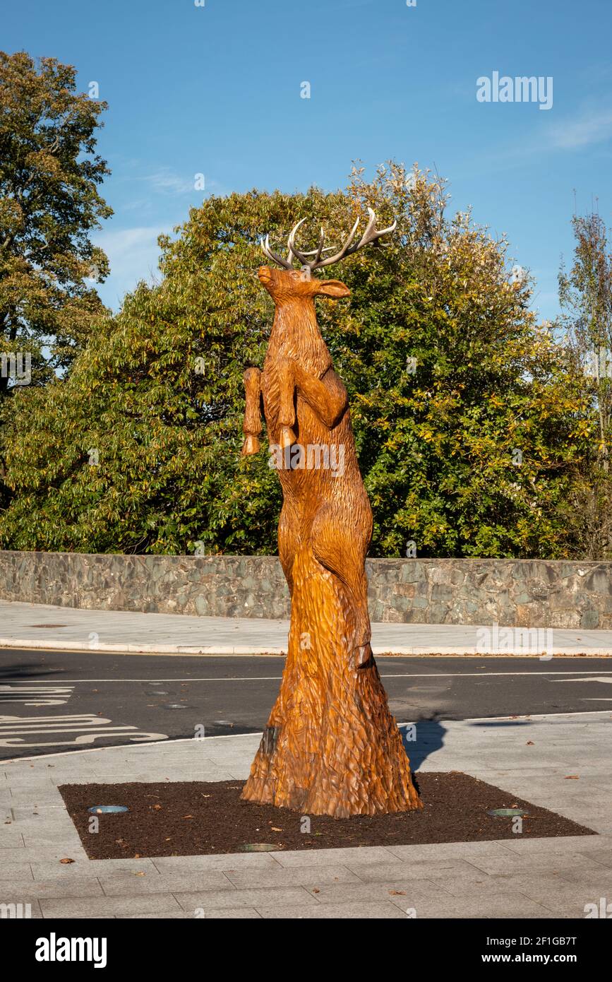 Creative sculpture of a red stag leaping into the air, carved entirely from an existing tree on Mission Road in Killarney, County Kerry, Ireland Stock Photo