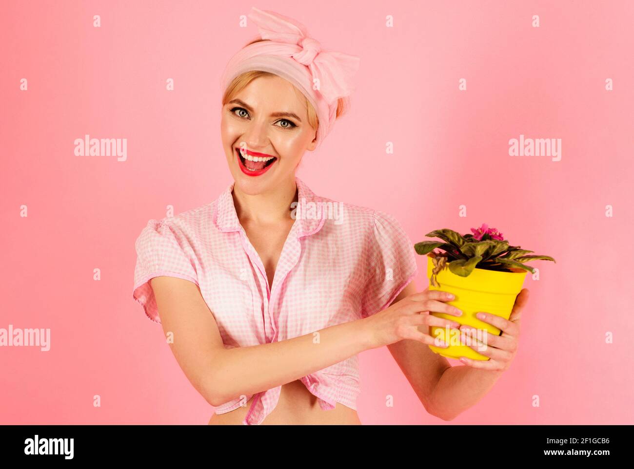 Smiling woman with violet flower in pot. Girl cultivating flowers. Planting. Stock Photo