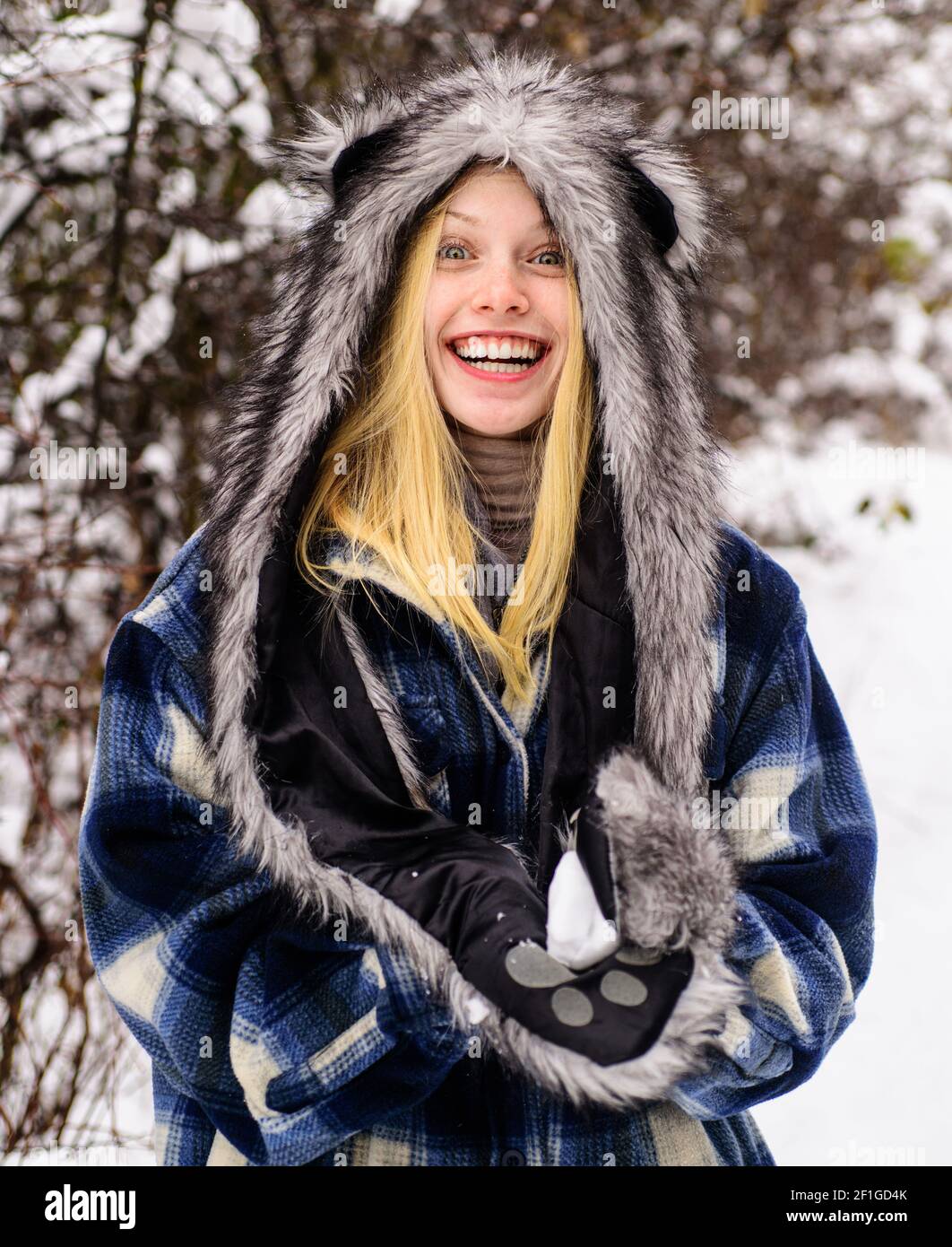 Wintertime. Smiling woman in warm clothing with snowball. Girl playing with snow. Season of winter. Stock Photo