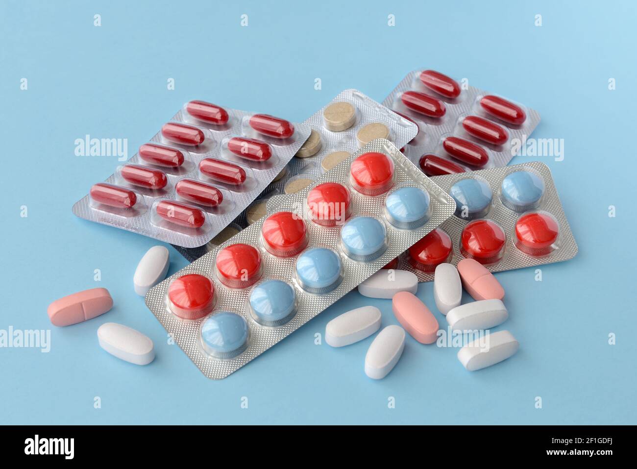 Assorted pharmaceutical medicine pills, tablets and capsules over blue background Stock Photo