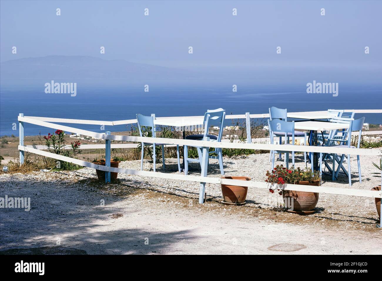 Blue Chairs surrounding rounded table overlooking the Caldera, Oia, Santorini, Thira, Cyclades Islands, Greek Islands, Greece, EU, Europe Stock Photo