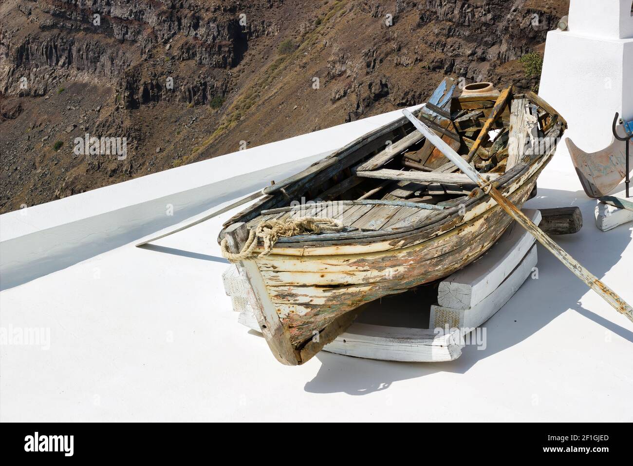 Santorini, Greece: A wrecked Boat on a roof at Firostefani near Fira on a greek island named Santorini. In the background is Skaros Rock mountain of I Stock Photo