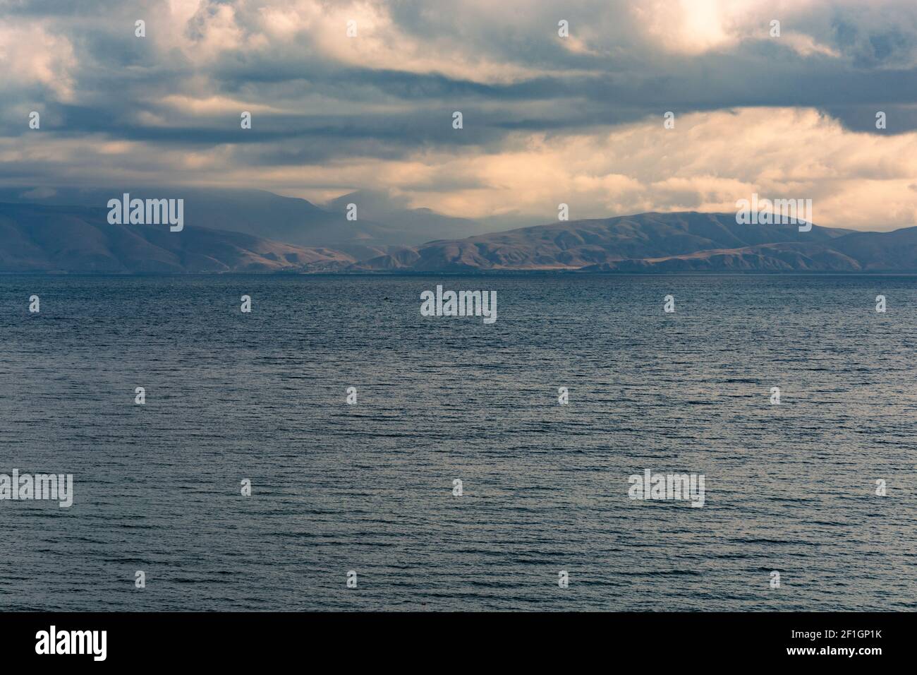An aerial view of a blue sea under a cloudy sky with hills in the ...