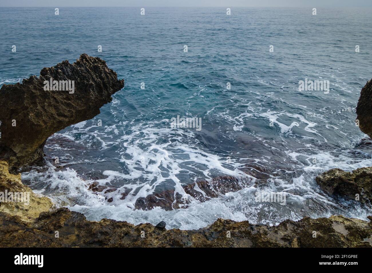 Coastline reefs & dark blue waves of Mediterranean sea. Horizon line on background Stock Photo