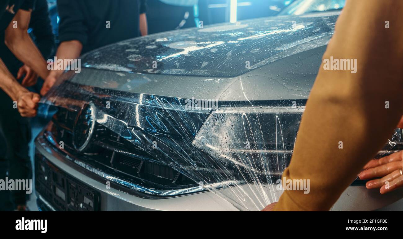 Paint Protection Film or PPF polymer protection coating layer, installing and wrapping on car hood in Detailing Garage. Stock Photo