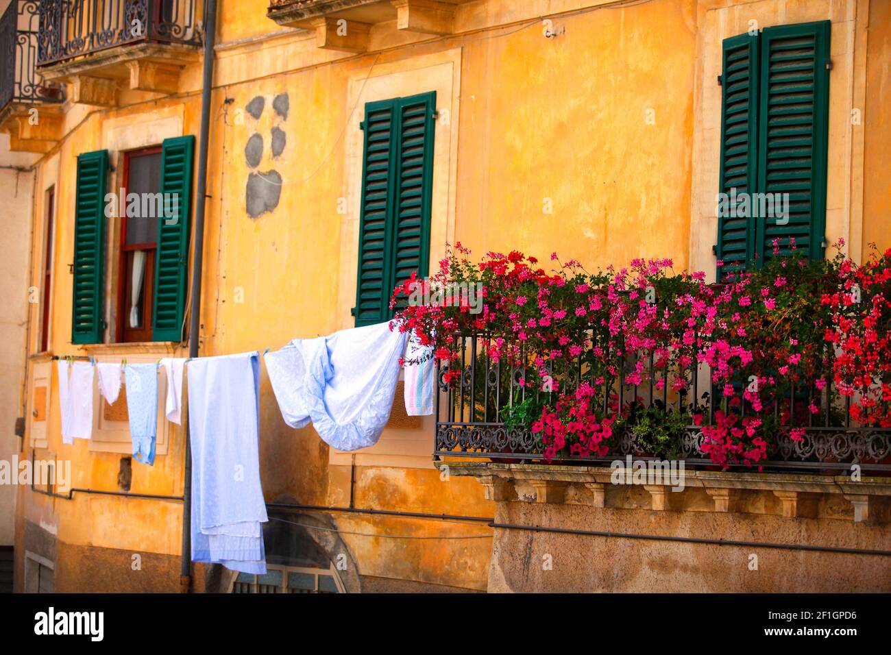 Washing hanging next to geraniums in Fontecchio, Abruzzo, Italy. Stock Photo