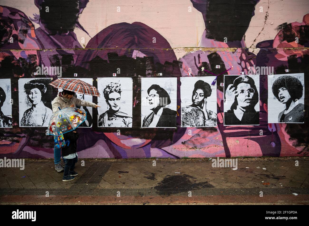 Madrid, Spain. 8th March, 2021. A woman shows her son a feminist mural that appeared today vandalized during International Women's Day. Placards of women have been placed over the paintings after the mural was vandalized with black paint. The mural represents famous women from around the world, with the faces of 15 women who are part of history for their fight in favor of equality: Credit: Marcos del Mazo/Alamy Live News Stock Photo