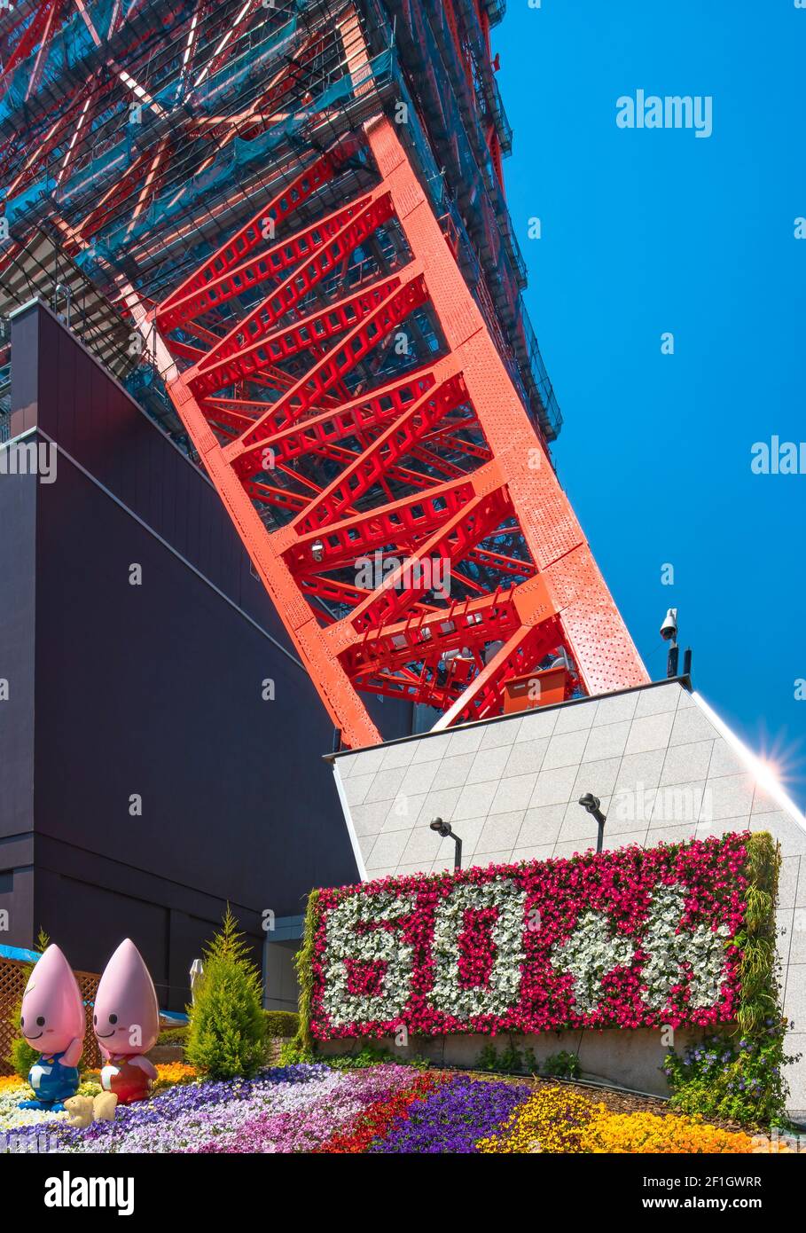 tokyo, japan - march 02 2021: Close up on the foot of the sightseeing landmark Tokyo tower adorned with colorful flowers and Noppon Brothers mascots f Stock Photo