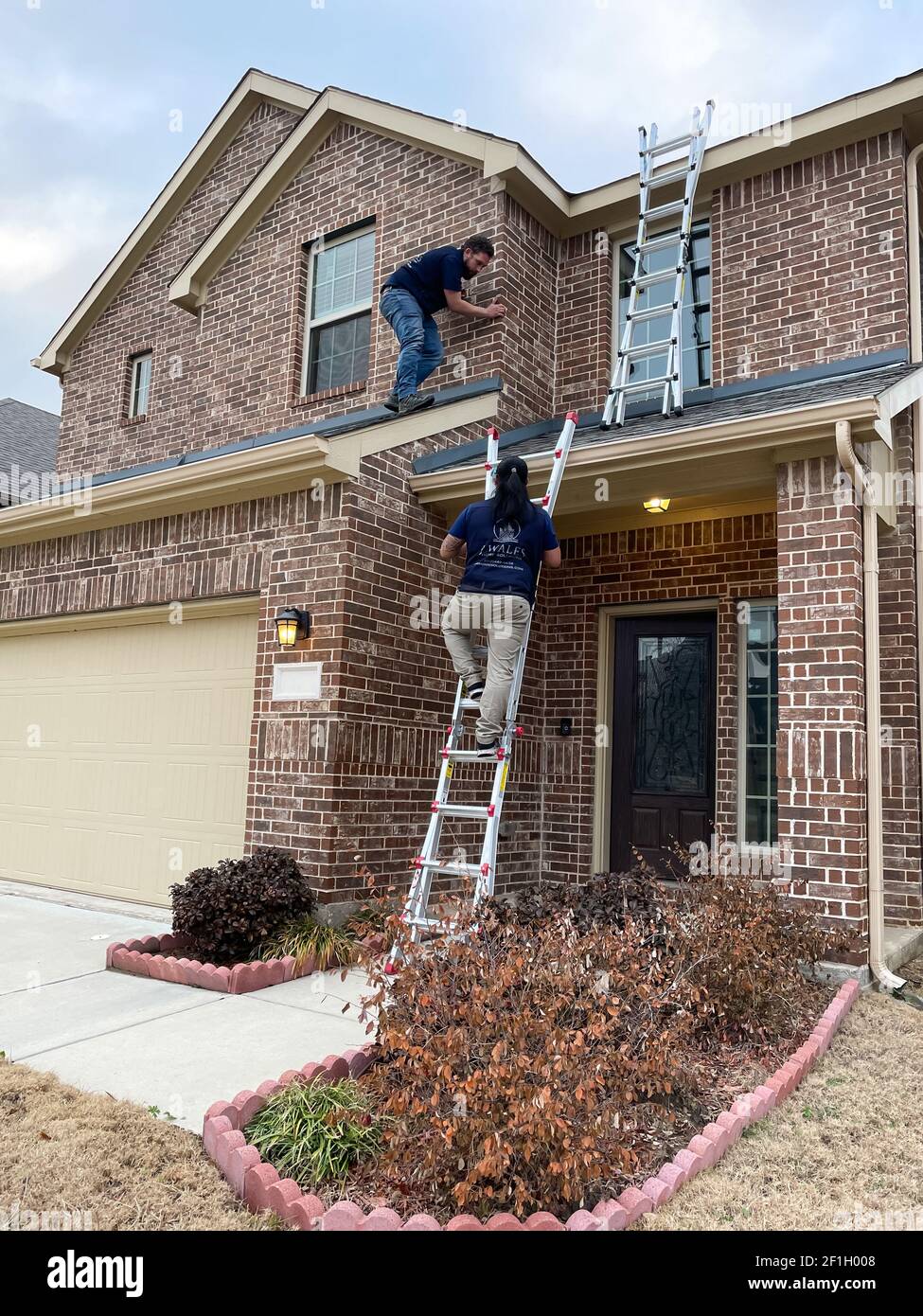 Mckinney, TX USA - March 1, 2021: Roof inspector climbing up to the roof to check the damage after a hail Stock Photo